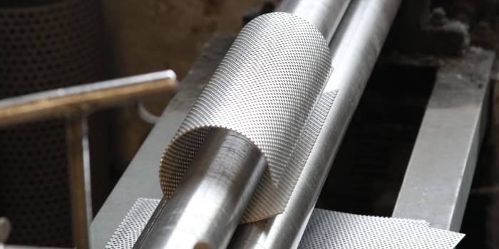 The machine is rolling the wire mesh into a cylindrical shape.