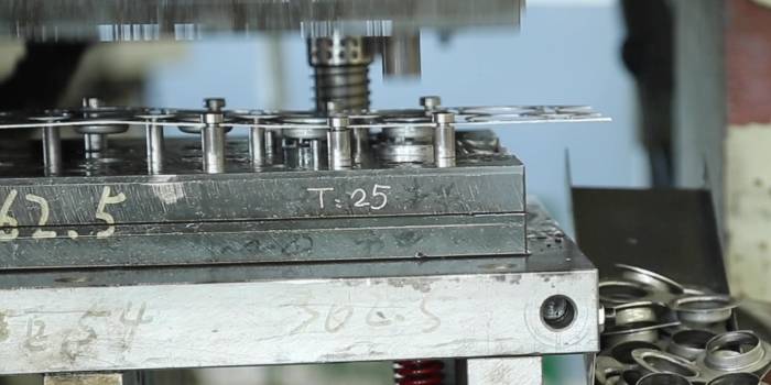 The stamping machine is pressing the metal sheet into caps for filter elements.