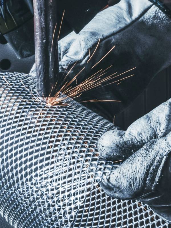 The worker is welding the cylindrical filter element.