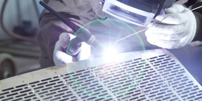 The worker is welding the perforated metal with TIG welding technology.