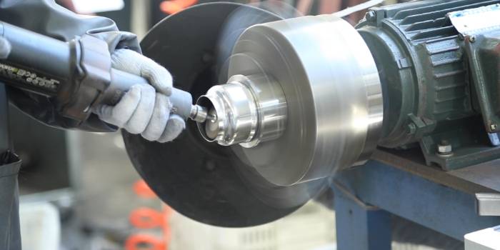 The worker is polishing the metal part.